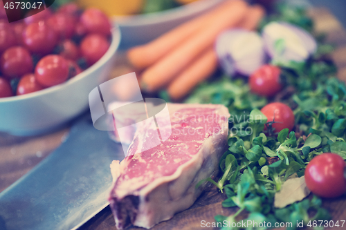 Image of Juicy slice of raw steak on wooden table