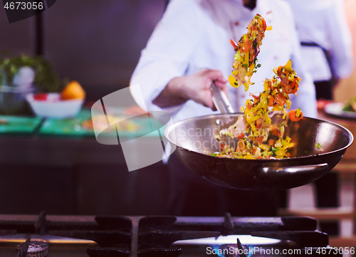 Image of chef flipping vegetables in wok