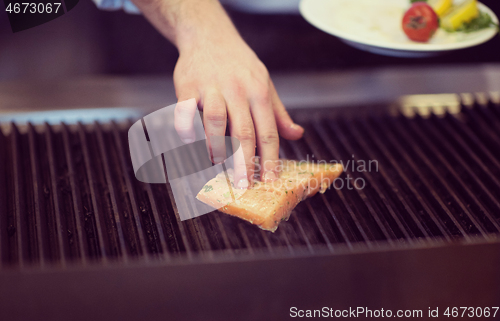 Image of chef hands cooking grilled salmon fish