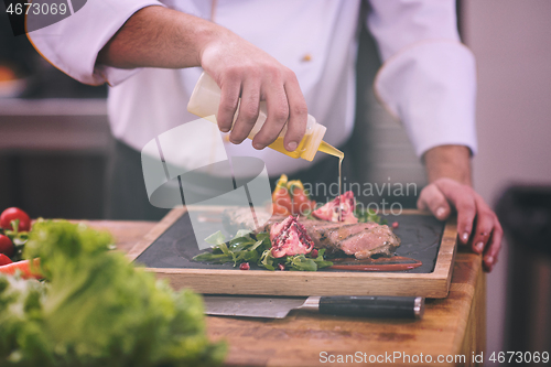 Image of Chef finishing steak meat plate