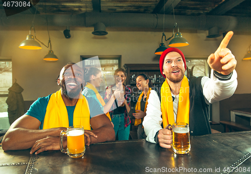 Image of Sport, people, leisure, friendship and entertainment concept - happy football fans or male friends drinking beer and celebrating victory at bar or pub