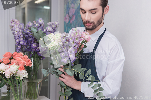 Image of Small business. Male florist in flower shop. Floral design studio, making decorations and arrangements.