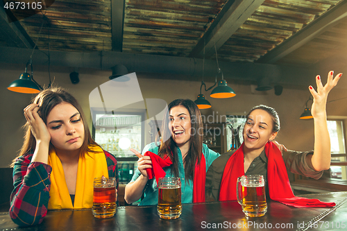 Image of Sport, people, leisure, friendship and entertainment concept - happy football fans or female friends drinking beer and celebrating victory at bar or pub