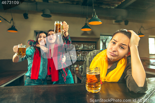 Image of Sport, people, leisure, friendship and entertainment concept - happy football fans or female friends drinking beer and celebrating victory at bar or pub