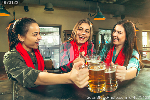Image of Sport, people, leisure, friendship and entertainment concept - happy football fans or female friends drinking beer and celebrating victory at bar or pub
