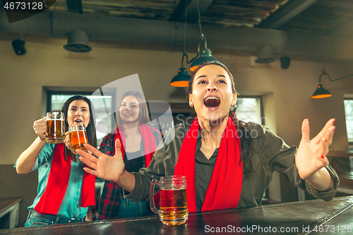 Image of Sport, people, leisure, friendship and entertainment concept - happy football fans or female friends drinking beer and celebrating victory at bar or pub