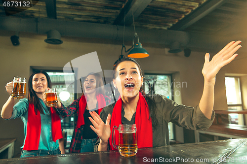 Image of Sport, people, leisure, friendship and entertainment concept - happy football fans or female friends drinking beer and celebrating victory at bar or pub