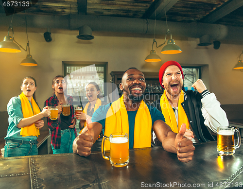 Image of Sport, people, leisure, friendship and entertainment concept - happy football fans or male friends drinking beer and celebrating victory at bar or pub