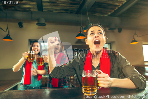 Image of Sport, people, leisure, friendship and entertainment concept - happy football fans or female friends drinking beer and celebrating victory at bar or pub