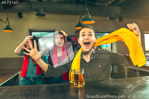 Image of Sport, people, leisure, friendship and entertainment concept - happy football fans or female friends drinking beer and celebrating victory at bar or pub