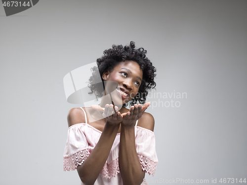 Image of The happy african woman standing and smiling against gray background.