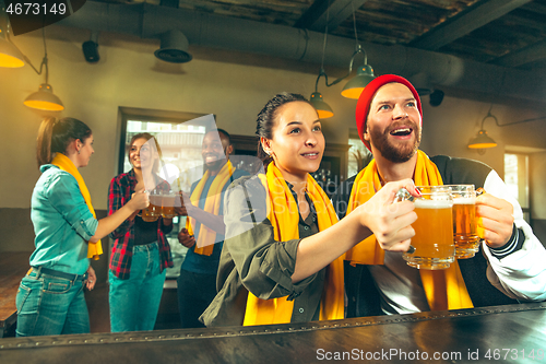 Image of Sport, people, leisure, friendship and entertainment concept - happy football fans or male friends drinking beer and celebrating victory at bar or pub