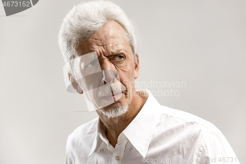 Image of The serious businessman standing and looking at camera against gray background.