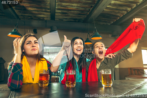 Image of Sport, people, leisure, friendship and entertainment concept - happy football fans or female friends drinking beer and celebrating victory at bar or pub