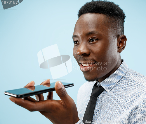 Image of Indoor portrait of attractive young black man holding blank smartphone