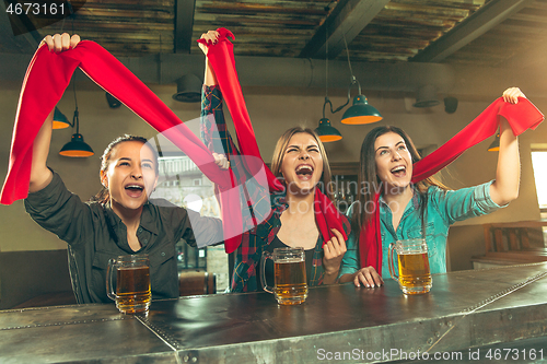 Image of Sport, people, leisure, friendship and entertainment concept - happy football fans or female friends drinking beer and celebrating victory at bar or pub