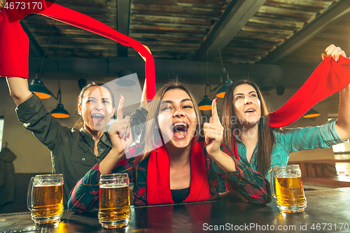 Image of Sport, people, leisure, friendship and entertainment concept - happy football fans or female friends drinking beer and celebrating victory at bar or pub