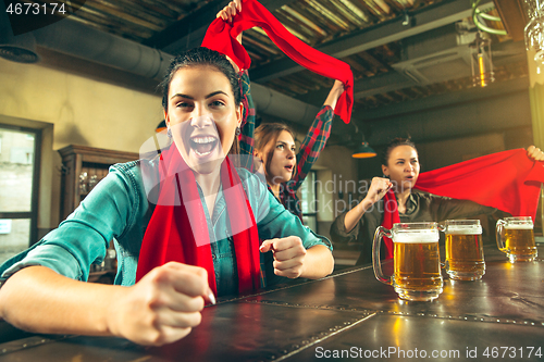 Image of Sport, people, leisure, friendship and entertainment concept - happy football fans or female friends drinking beer and celebrating victory at bar or pub