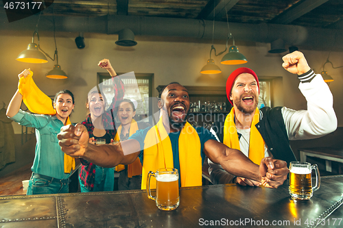 Image of Sport, people, leisure, friendship and entertainment concept - happy football fans or male friends drinking beer and celebrating victory at bar or pub