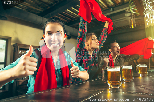 Image of Sport, people, leisure, friendship and entertainment concept - happy football fans or female friends drinking beer and celebrating victory at bar or pub