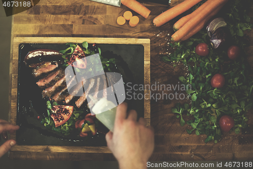 Image of top view of Chef finishing steak meat plate