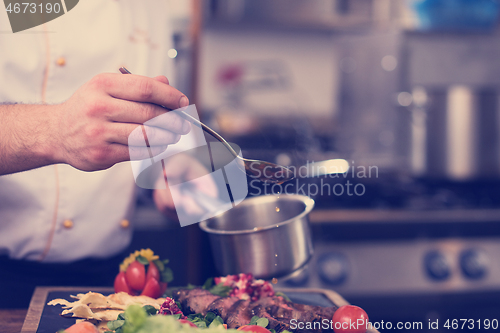 Image of Chef hand finishing steak meat plate