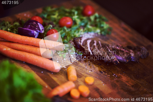 Image of Juicy slices of grilled steak on wooden board