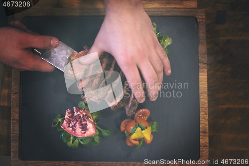 Image of top view of Chef hands serving beef steak