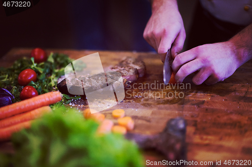 Image of closeup of Chef hands preparing beef steak