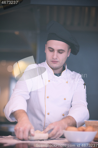 Image of young chef preparing dough for pizza