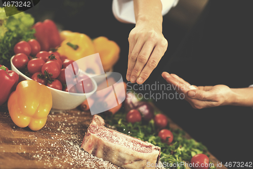 Image of Chef putting salt on juicy slice of raw steak