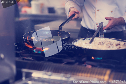 Image of chef preparing food, frying in wok pan