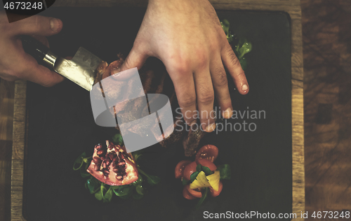 Image of top view of Chef hands serving beef steak