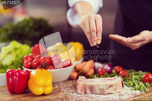 Image of Chef putting salt on juicy slice of raw steak