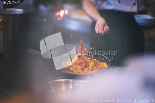 Image of chef flipping vegetables in wok