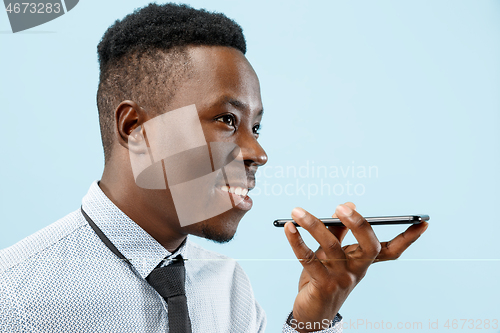 Image of Indoor portrait of attractive young black man holding blank smartphone