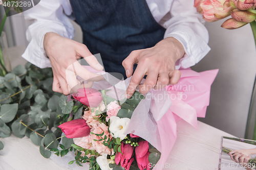 Image of Small business. Male florist in flower shop. Floral design studio, making decorations and arrangements.