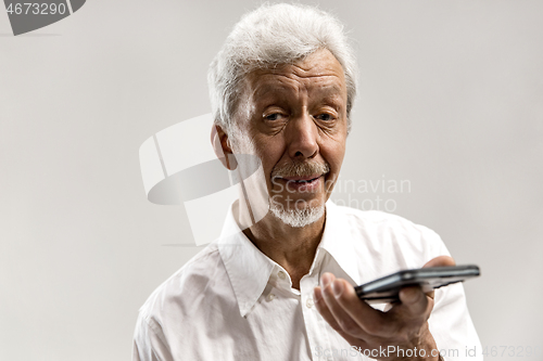 Image of Indoor portrait of senior man holding blank smartphone