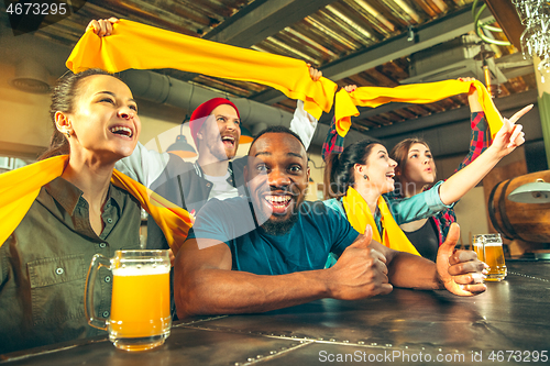 Image of Sport, people, leisure, friendship and entertainment concept - happy football fans or male friends drinking beer and celebrating victory at bar or pub