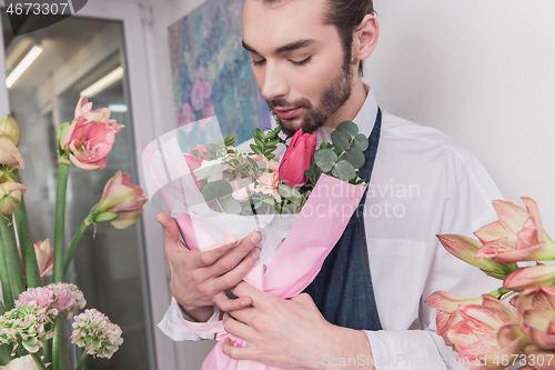 Image of Small business. Male florist in flower shop. Floral design studio, making decorations and arrangements.