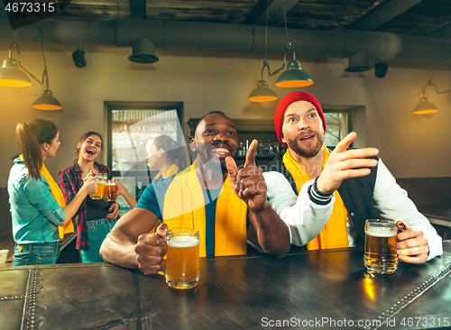 Image of Sport, people, leisure, friendship and entertainment concept - happy football fans or male friends drinking beer and celebrating victory at bar or pub