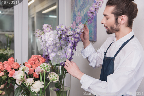 Image of Small business. Male florist in flower shop. Floral design studio, making decorations and arrangements.