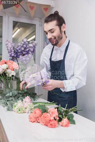 Image of Small business. Male florist in flower shop. Floral design studio, making decorations and arrangements.