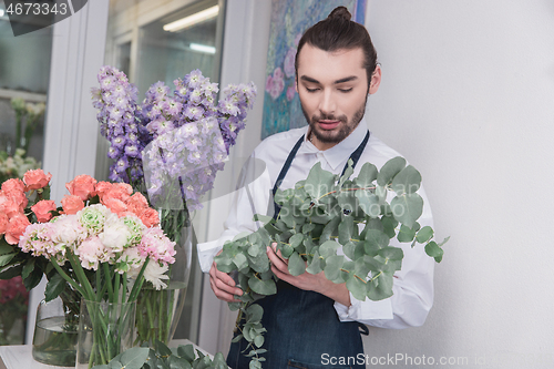 Image of Small business. Male florist in flower shop. Floral design studio, making decorations and arrangements.