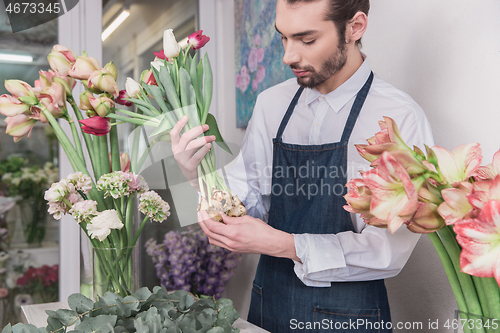 Image of Small business. Male florist in flower shop. Floral design studio, making decorations and arrangements.