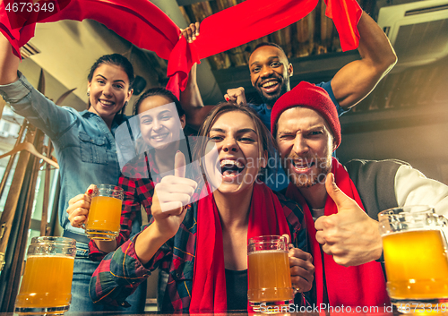 Image of Sport, people, leisure, friendship and entertainment concept - happy football fans or male friends drinking beer and celebrating victory at bar or pub