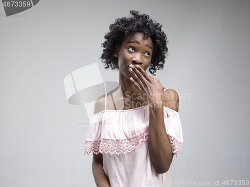 Image of The young woman whispering a secret behind her hand