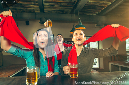 Image of Sport, people, leisure, friendship and entertainment concept - happy football fans or female friends drinking beer and celebrating victory at bar or pub