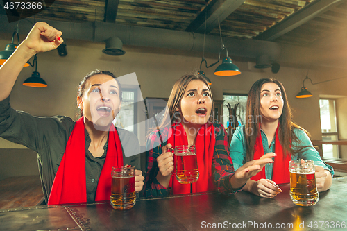 Image of Sport, people, leisure, friendship and entertainment concept - happy football fans or female friends drinking beer and celebrating victory at bar or pub