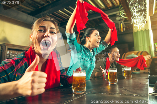 Image of Sport, people, leisure, friendship and entertainment concept - happy football fans or female friends drinking beer and celebrating victory at bar or pub